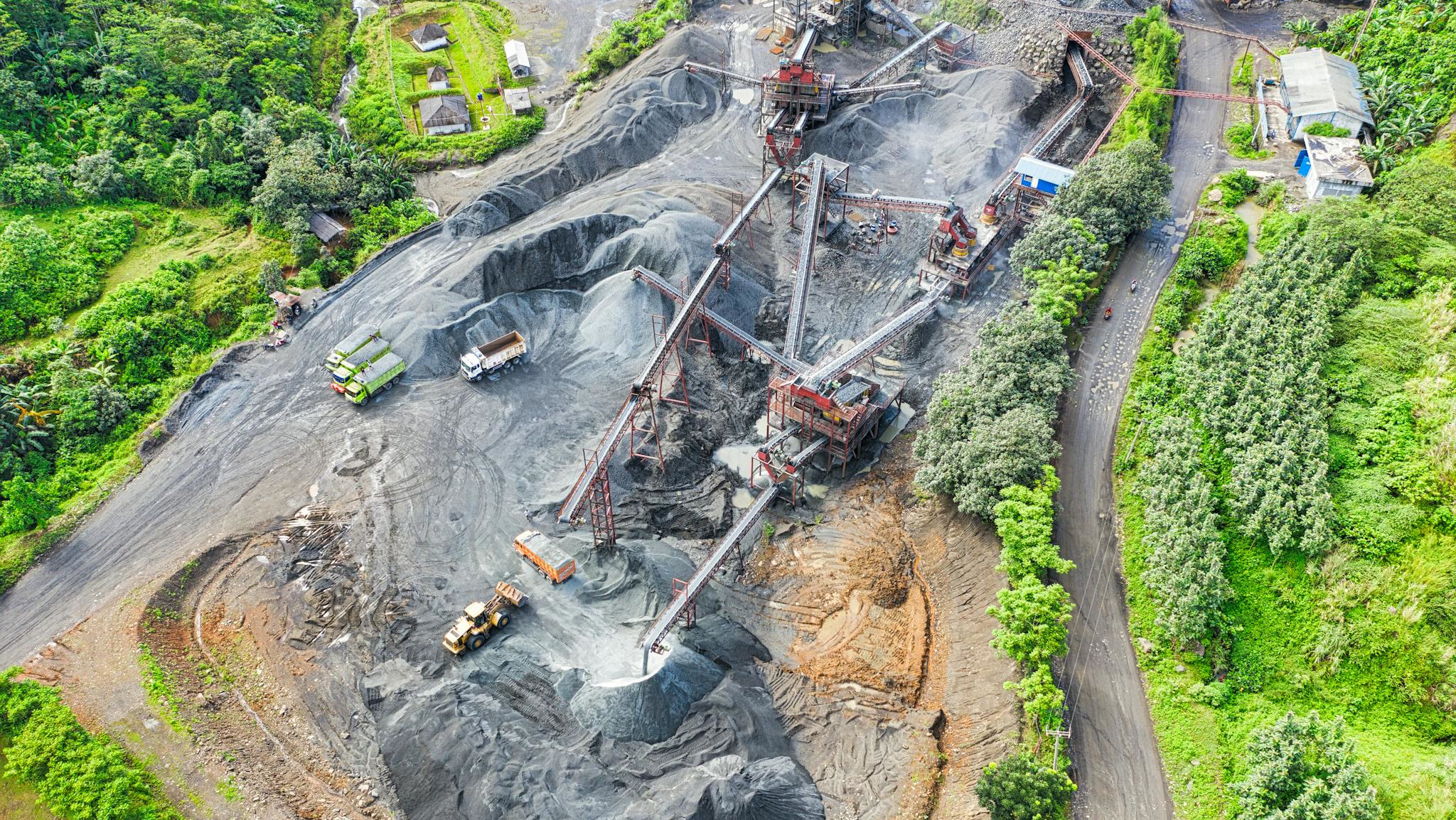 Aerial shot of a mining site surrounded by greenery, showcasing industrial activity.